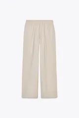 Pantalón de tiro alto color beige, con cintura elástica ajustable con cordones, bolsillos delanteros y pernera ancha.
