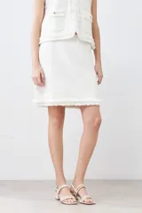 Falda corta color crudo tejida con textura acanalada horizontal y terminación desflecada en el ruedo.