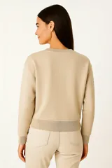 Buzo negro de cuello redondo y manga larga, con estampado frontal de la palabra "PARIS" en color lila con borde blanco.