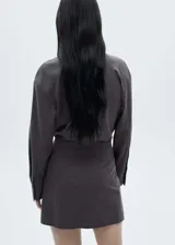 Minivestido gris con estampado de raya diplomática, diseño cruzado con cierre de botones en la parte delantera, manga larga con puños abotonados, cuello camisero y diseño entallado.