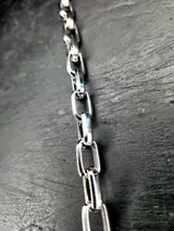 Pulsera plateada de acero inoxidable con eslabones medianos pulidos y cierre de mosquetón.