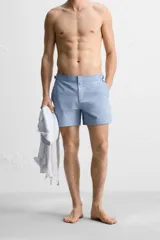 Bañador corto celeste de tejido técnico con cintura elástica ajustable con cordón interior y trabillas laterales. Cuenta con bolsillos frontales, bolsillo trasero con cierre de cremallera y forro interior.