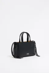 Bolso de mano Bimba y Lola modelo Chihuahua, tamaño mini, color negro, fabricado en piel con piezas de metal plateado. Presenta estructura blanda, cierre con cinta de piel, logo metálico, bolsillo interior con cremallera e interior con logo grabado.