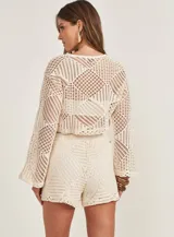 Sweater tejido a crochet color beige, de mangas largas acampanadas y corte crop.