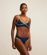 Soutien deportivo azul con breteles finos ajustables, base larga y detalles contrastantes en color blanco.
