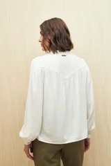 Camisa celeste de manga larga en viscosa suave, con cuello mao y botonadura parcial al frente. El detalle de frunces en los hombros y los puños abotonados le suman delicadeza y estilo.