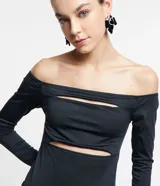 Vestido midi de jersey negro, con escote hombro a hombro, mangas largas, aberturas en el busto y tajo en la espalda.
