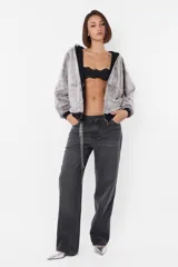 Campera oversize de piel sintética color gris, con capucha y bolsillos delanteros. Acceso frontal mediante cierre metálico YKK con tiracierre personalizado logo de marca. Cordones al tono con punteras metálicas marcarias y ojalillos personalizados color niquel. Forrada cuerpo y capucha en Jersey con Rib en cintura y puños al tono.