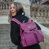 Mochila de poliéster color púrpura con solapa y sujetador. Tiene un bolsillo interno con cierre, dos bolsillos internos abiertos y dos bolsillos externos con cierre. La correa es regulable y los herrajes son plateados. El interior es de tela de algodón y poliéster.