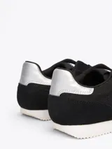 Zapatillas Tommy Jeans de corte bajo, color negro con detalles en blanco y plateado. Capellada de poliéster con paneles de malla y ante.