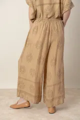 Pantalón palazzo de lino color crudo con estampado floral al tono, tiro alto y cintura elastizada.