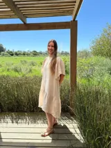 Vestido largo color beige, de corte suelto, con mangas cortas abullonadas y volado en el ruedo.