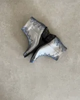 Botín de cuero vacuno color bronce con puntera y caña en cuero negro. Diseño con borde superior en zigzag y taco de madera.