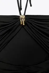 Vestido midi negro confeccionado en hilatura con mezcla de poliamida. Escote recto y tirantes finos ajustables con lazadas. Detalle de aplicación metálica en delantero y cut out. Drapeado lateral.