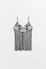 Top negro de encaje floral semitransparente con tirantes finos ajustables y escote en pico.