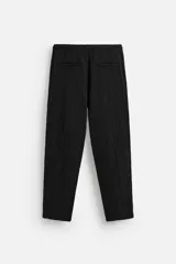 Pantalón negro de corte amplio, con textura acanalada, cintura elástica ajustable con cordón, bolsillos laterales y traseros de vivo.