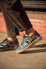 Zapatillas bajas de cuero con estampado animal print y detalles en cuero celeste.