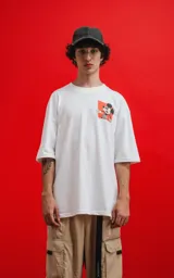 Remera blanca de algodón premium con cuello redondo y calce oversize. Presenta un pequeño estampado en el pecho izquierdo de Mickey Mouse en una pose dinámica sobre un fondo naranja.