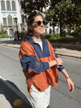Buzo de algodón color naranja y azul marino, con cierre parcial en el cuello y puños ajustados.