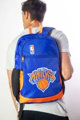 Mochila de nylon azul con detalles naranjas y bolsillo frontal. Presenta el logo de la NBA y el logo del equipo New York Knicks.