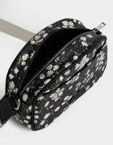Bandolera negra con estampado de flores blancas, correa de algodón ajustable y cierre superior.