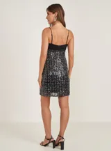 Vestido corto negro con breteles finos y escote recto. Falda con lentejuelas plateadas.