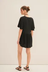 Vestido corto negro con escote en V y efecto foil. Presenta mangas amplias tipo mariposa y un corte holgado con frunce bajo el busto.