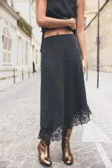 Falda midi gris oscuro de tejido de punto, con cintura elástica y bajo asimétrico con detalle de encaje negro.