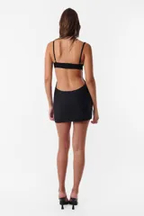 Vestido corto negro de microfibra, ajustado al cuerpo, con breteles elásticos regulables, recortes en el delantero y corpiño inferior de encaje. Espalda descubierta.