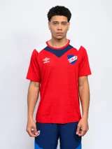 Remera de entrenamiento con cortes y cambios de color. Logo de Umbro bordado en el pecho. Escudo del Club Nacional de Football estampado en el pecho. Cuello redondo. Mangas cortas. Corte clásico.