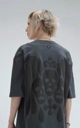 Remera negra de corte holgado con estampado de calaveras y cruz en el frente.