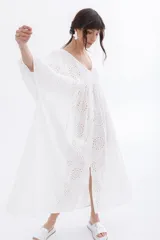 Vestido largo blanco con bordado calado tipo broderie, escote en V y mangas largas abullonadas.