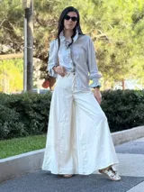 Pantalón ancho color crudo con pespuntes en marrón chocolate, confeccionado en tela con mezcla de jean y lino.