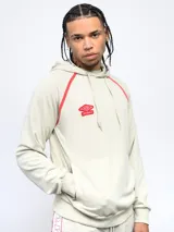 Canguro de felpa color crema con capucha, cordones y logo Umbro bordado en rojo. Presenta ribete rojo en hombros y bolsillo tipo canguro con cierre lateral.