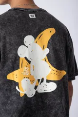 Remera color verde oliva con efecto gastado, de corte recto y mangas cortas. Estampado en la espalda con un dibujo de Mickey Mouse y una banana. Logo de la marca en el frente.