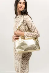 Bolso tipo shopper dorado de cuero natural, sin forro, con base plana y doble asa de hombro.