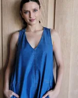 Vestido largo color crudo, sin mangas y con escote en V. Presenta aberturas laterales en el ruedo y bolsillos laterales a la altura de la cadera.