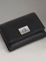 Billetera triple Calvin Klein de cuero sintético texturizado color negro, con logo metálico plateado. Incluye seis ranuras para tarjetas, dos ranuras para billetes y un compartimento para monedas con cremallera.