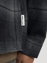 Sobrecamisa de manga larga a cuadros grises y negros, con cuello clásico, cierre frontal con botones y dos bolsillos de parche en el pecho.