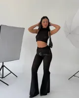 Conjunto de top corto y pantalón acampanado de encaje negro con cinturón de tachas.