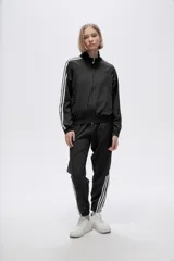 Campera deportiva verde con cierre frontal, cuello alto y tres rayas blancas en las mangas.