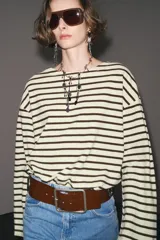 Camiseta de manga larga a rayas horizontales blancas y negras, con cuello redondo y bajo con aberturas laterales.