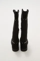 Botas texanas negras de caña media, confeccionadas en gamuza. Presentan un diseño de estilo western con detalles de tachas metálicas plateadas decorando el borde superior y el contorno del empeine. Tienen un taco bajo y punta ligeramente afilada.