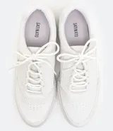 Zapatilla deportiva blanca de mujer, estilo casual, con cordones satinados y suela de plataforma gruesa con textura acanalada.