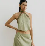 Top verde claro de lino con cuello halter y tiras para atar en la espalda. Presenta puntilla y galones bordados en el cuello y sisas.