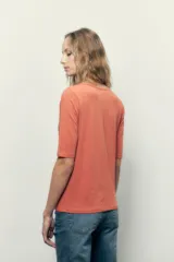 Remera blanca de manga corta con escote redondo y cordones cruzados con ojalillos metálicos.