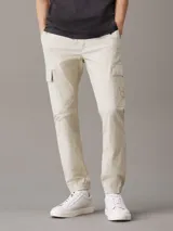 Pantalón cargo color beige de corte skinny, con cintura y puños elásticos, cierre de cremallera y botón de presión, bolsillos delanteros y traseros, bolsillos cargo con solapa, acabado ligeramente lavado e insignia con el monograma de Calvin Klein en la pierna.