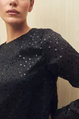 Blusa negra de manga larga con cuello redondo y lentejuelas a tono.