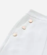 Bermuda de crepé color rojo, con pliegues frontales y botones decorativos en los bolsillos laterales.