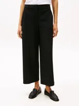 Pantalón negro de corte amplio, tobillero y talle bajo. Confeccionado en tejido antiarrugas de mezcla de viscosa elástica. Presenta cierre de cremallera con enganche oculto, raya marcada en la parte delantera y trasera, y dos bolsillos traseros de ojal.